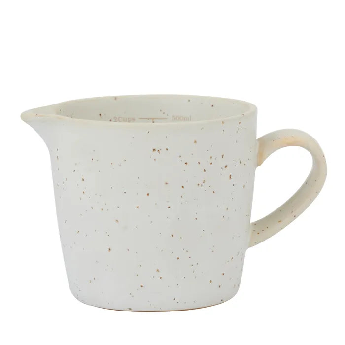Speckled ceramic pitcher on a white background